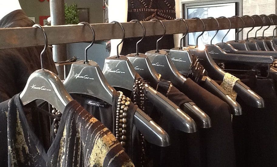 Black garments with decorative details on branded hangers in boutique.