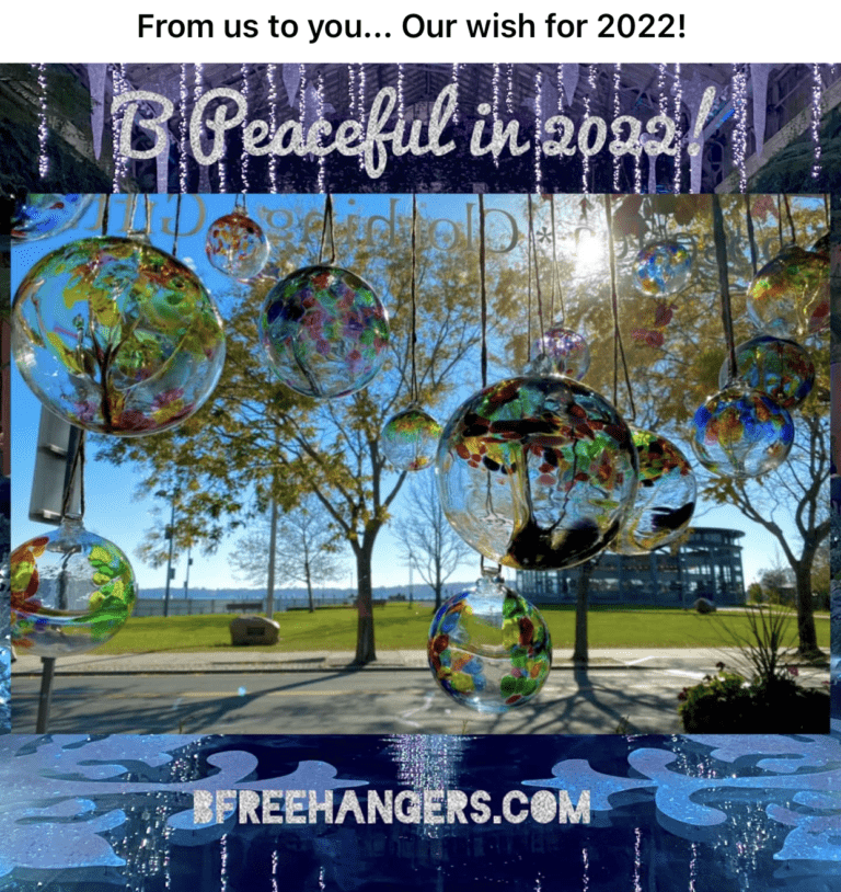Colorful glass orbs hang in sunlight, framed by trees and a park landscape, conveying a peaceful 2022 wish. Sign at the bottom promotes BFreeHangers.com.
