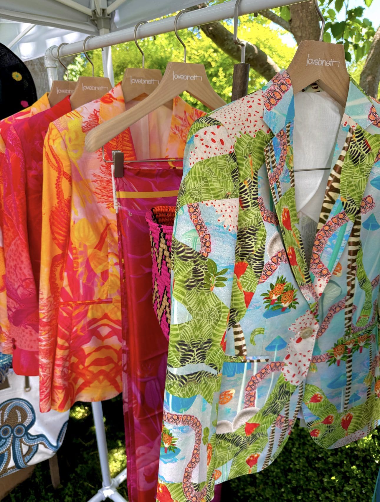 Colorful patterned blazers hang under canopy, showcasing vibrancy.