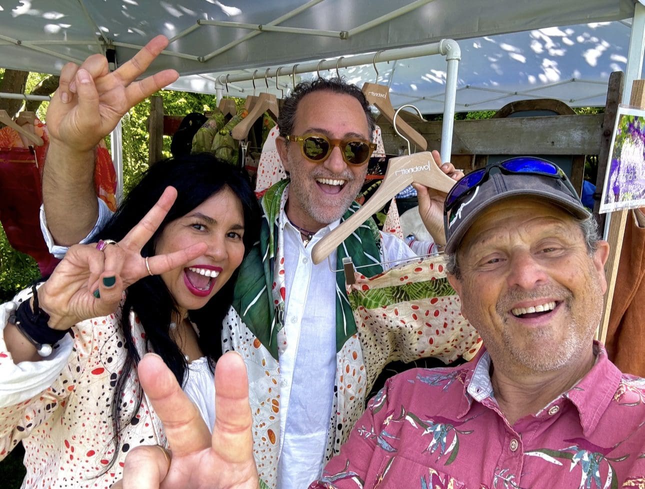 Three smiling people pose playfully under canopy, festive.