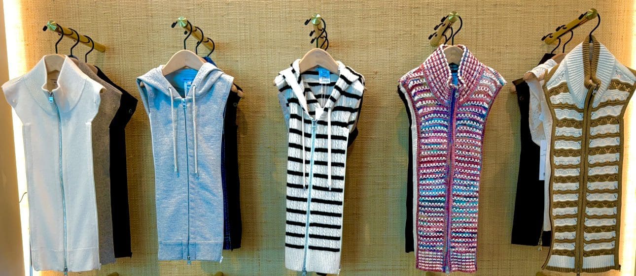 Sleeveless hoodies displayed on hangers in varied patterns.