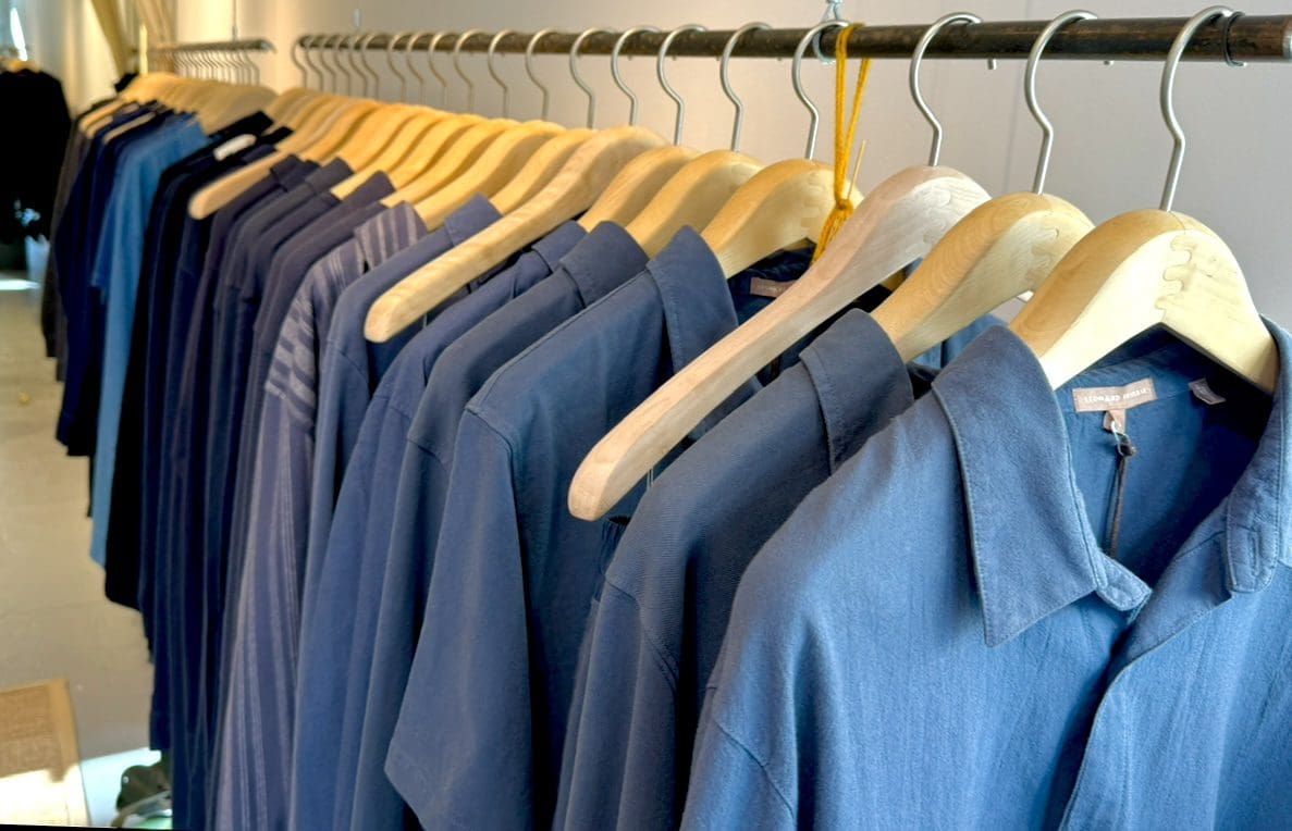 Blue shirts displayed on wooden hangers in store.