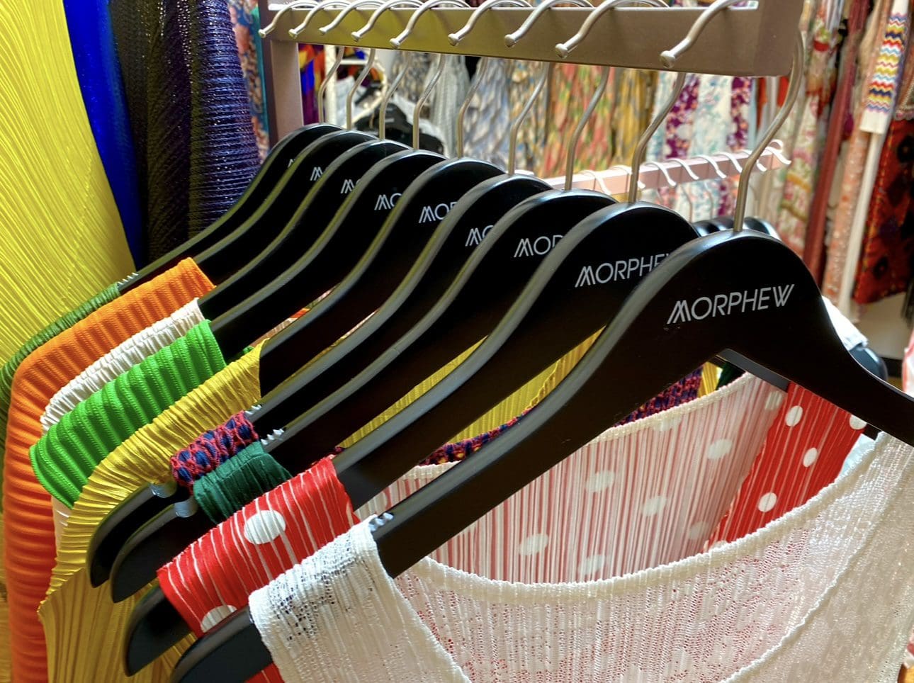 Bright dresses hang on black Morphew hangers retail.