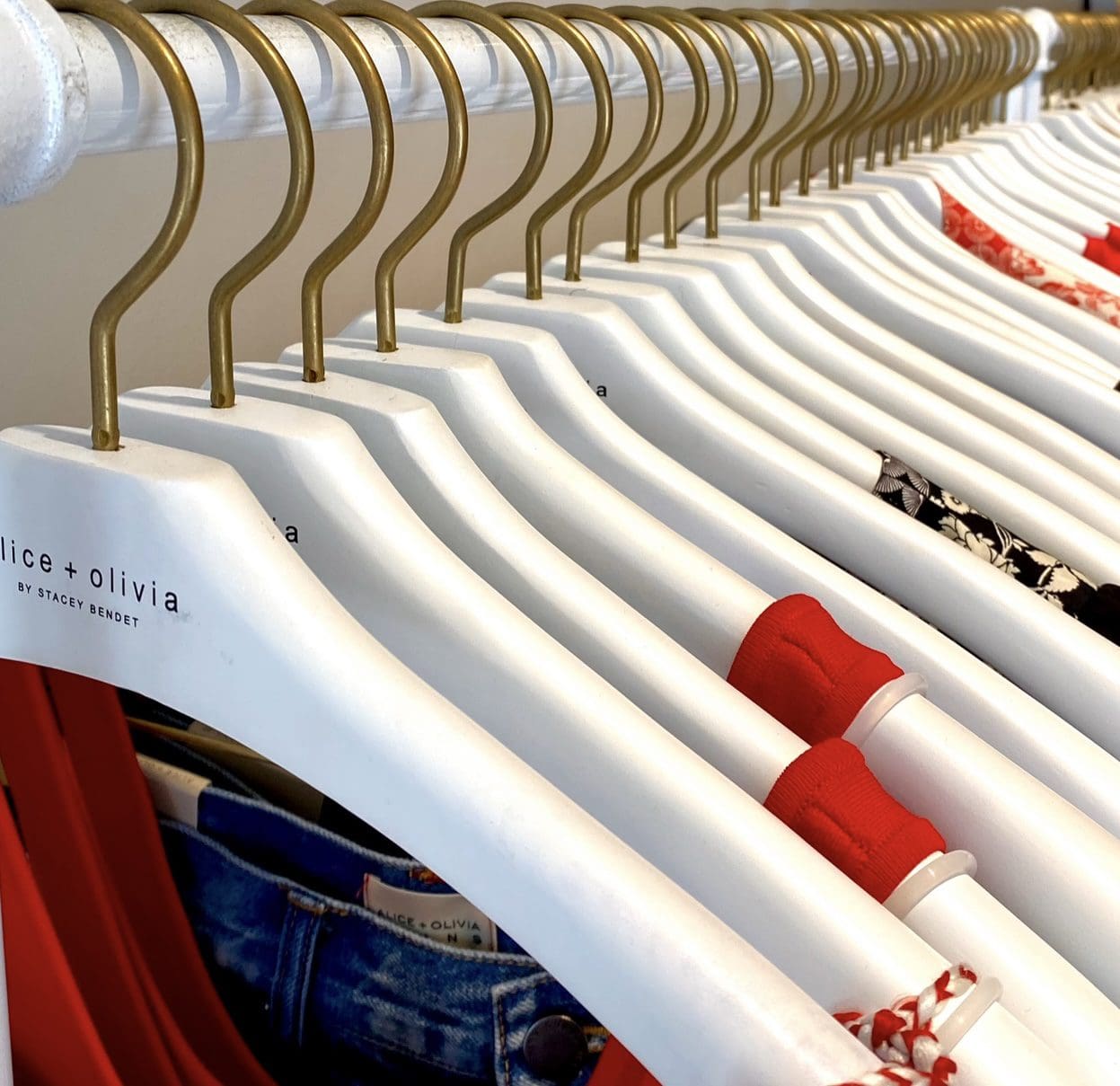 White hangers display red and floral clothes in retail.