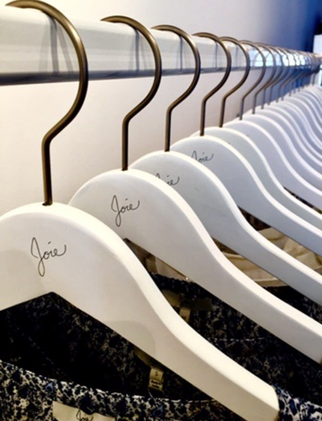 "Joie" white hangers display elegant clothes stylishly.