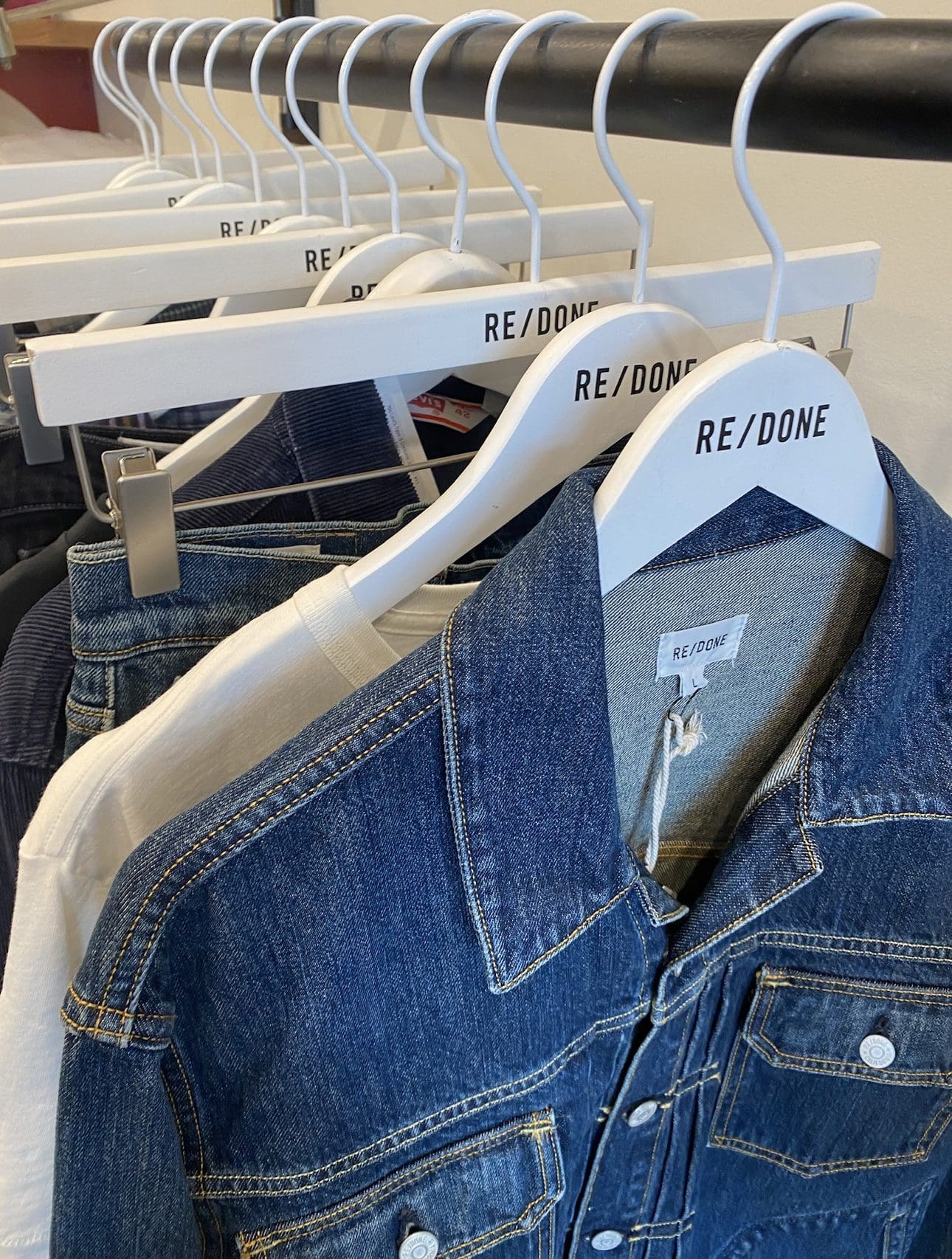 “RE/DONE” white hangers display denim jackets, shirts.