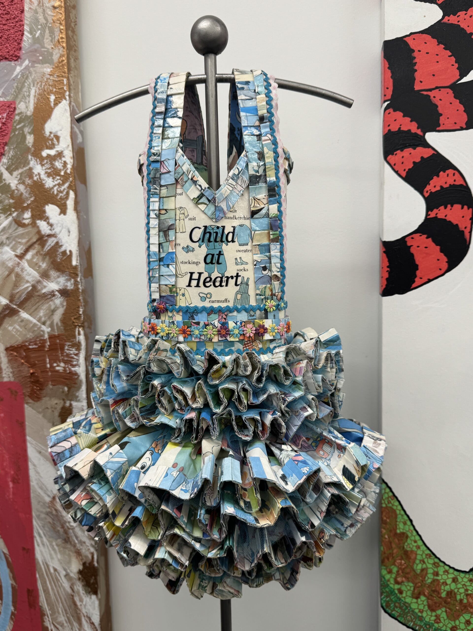 Colorful recycled dress displaying “Child at Heart” phrase.