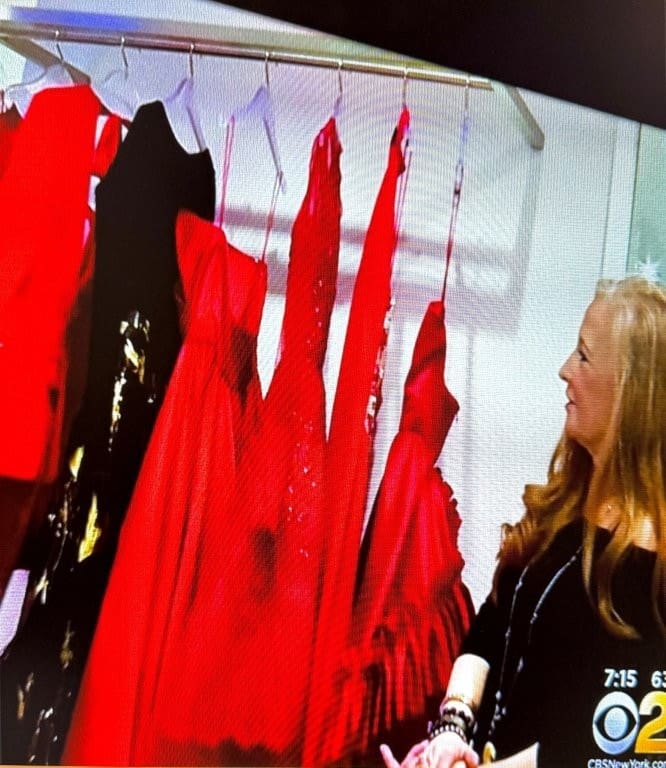 Woman admires diverse red dresses on clothing rack.