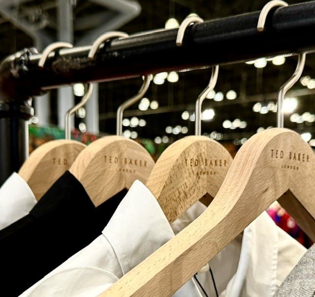 Ted Baker shirts on wooden hangers displayed retail setting, blurred background.