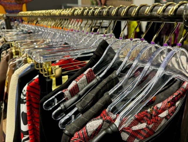 Clear plastic hangers hold vibrant fashion pieces on retail rack.