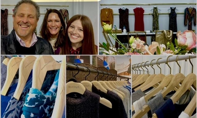 Three people smile amid boutique dresses and flowers.