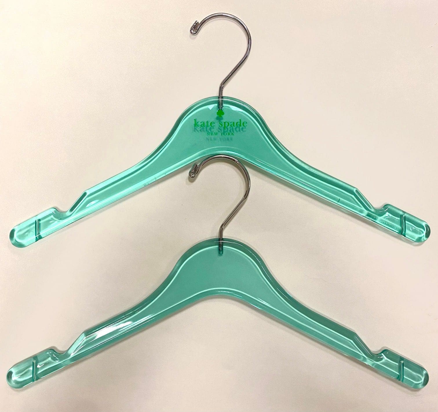 Kate Spade light blue plastic hangers stacked on a neutral background, showcasing the brand logo for stylish clothing display.