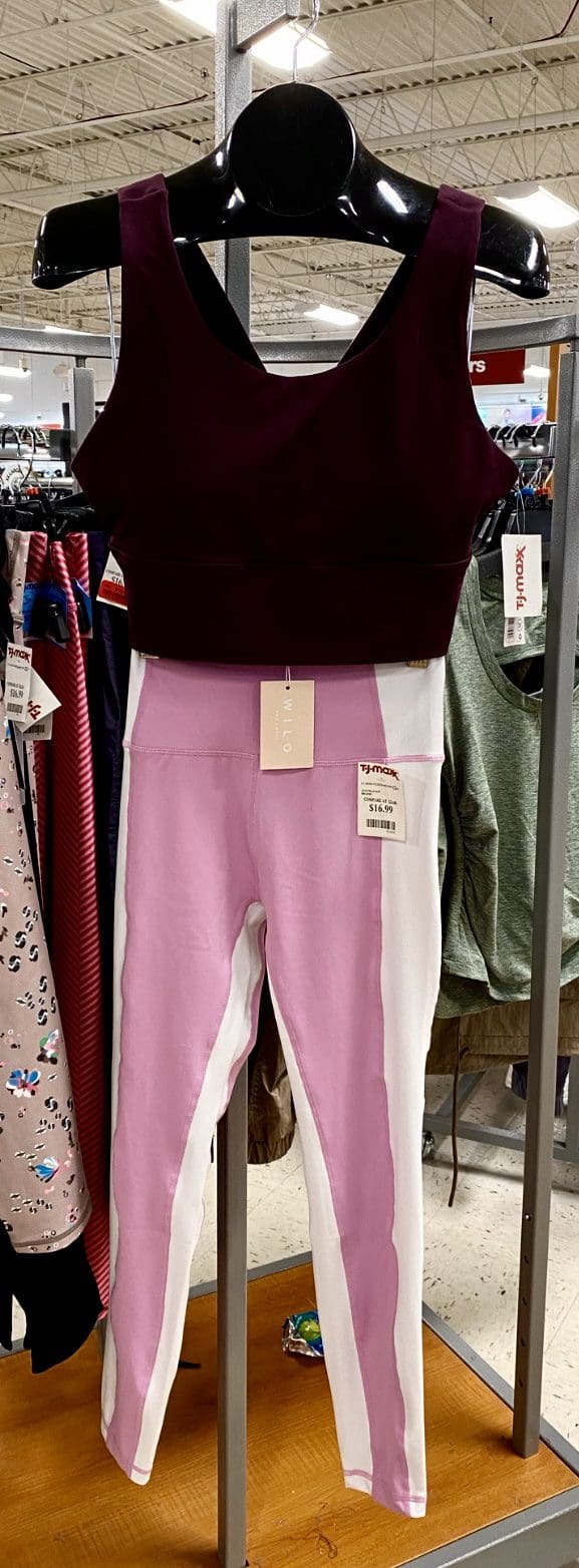 Maroon sports bra paired with pink and white leggings, displayed on a rack in a retail store. Price tag visible at $16.99.