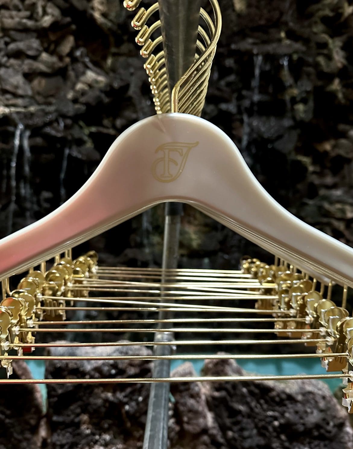 Gold-clip hangers on rack, rocky water backdrop.