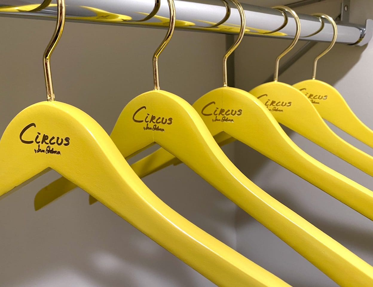 Bright yellow “Circus by Sam Gelman” hangers on rack.