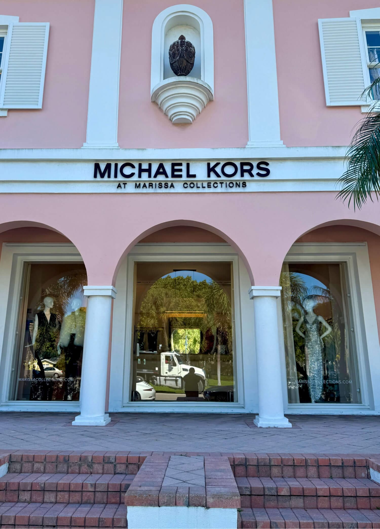Michael Kors boutique at Marissa Collections, elegant window displays, pink building backdrop.