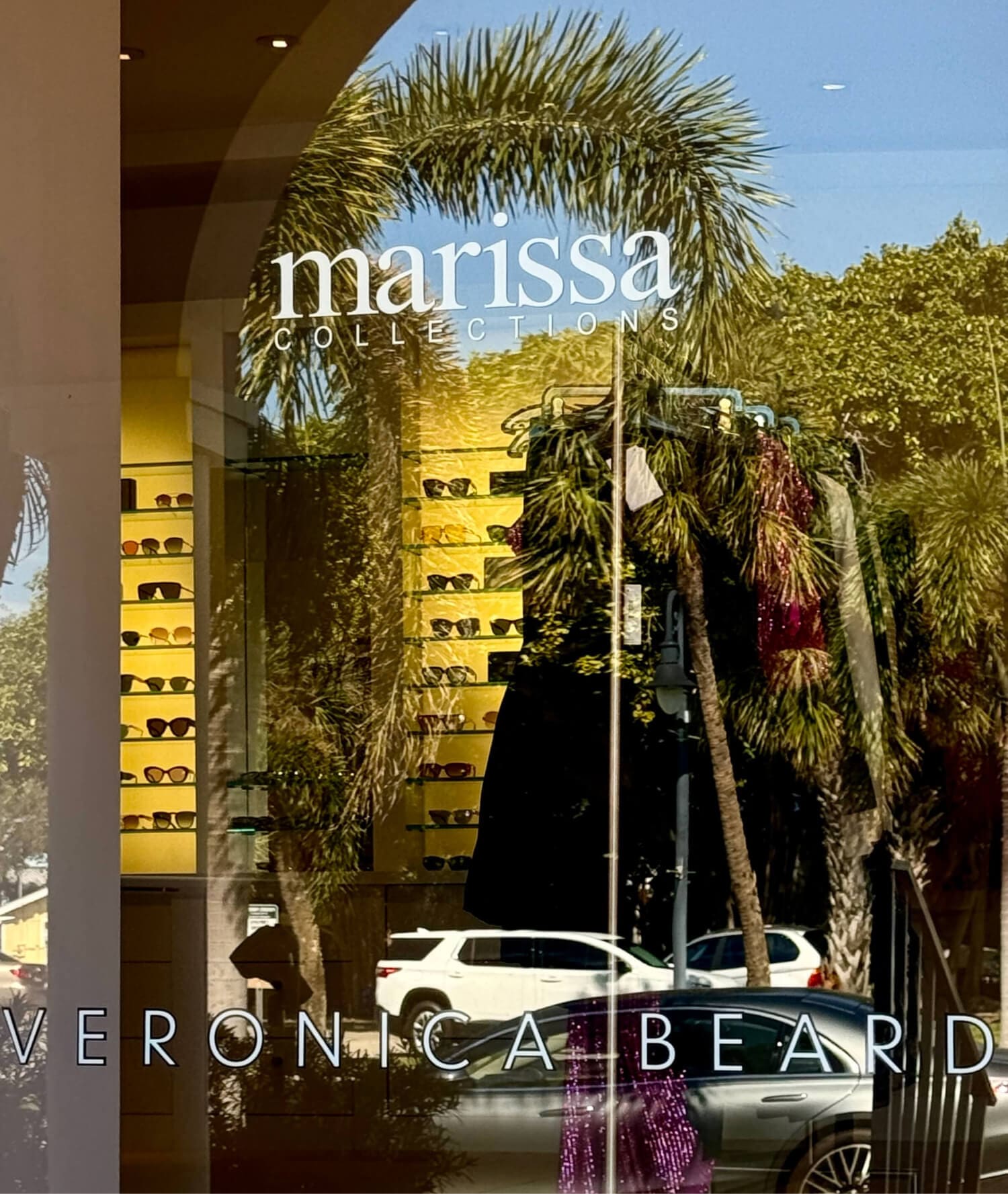 Marissa Collections storefront with sunglasses, Veronica Beard, palms.