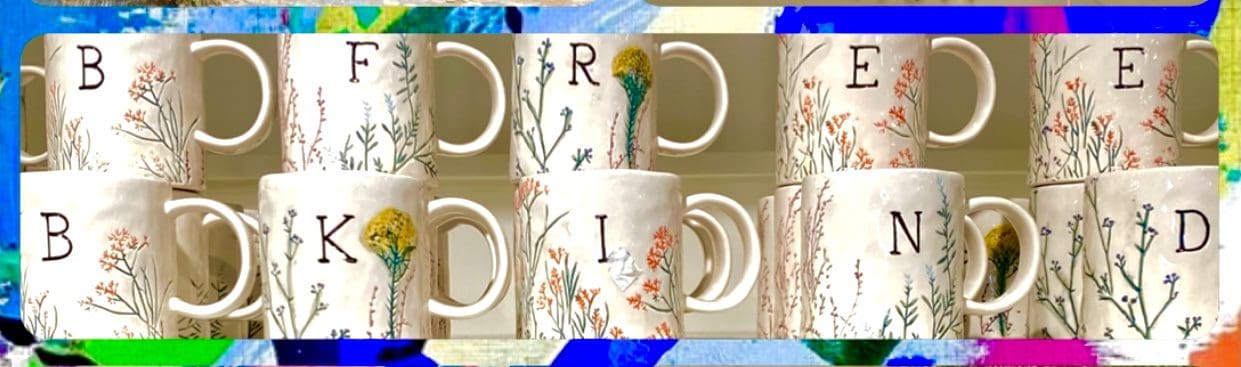 Mugs arranged to spell "BE KIND," featuring delicate floral designs, symbolize positivity and friendship. Ideal for motivational decor or gifting.