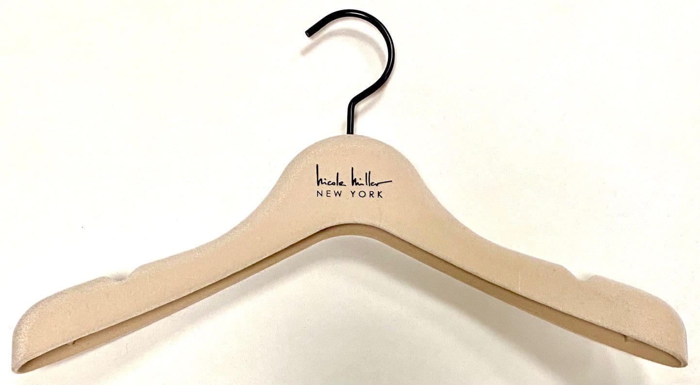 Cream-colored wooden hanger with a black hook, featuring the logo "Nicole Miller New York," ideal for showcasing fashion items.