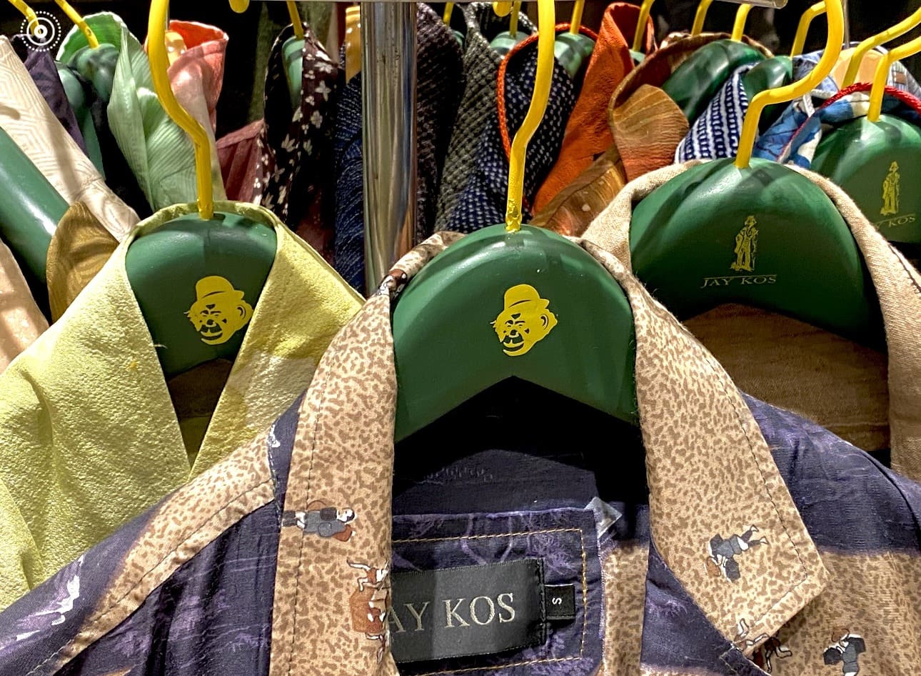 Colorful shirts on green hangers with playful caricatures.