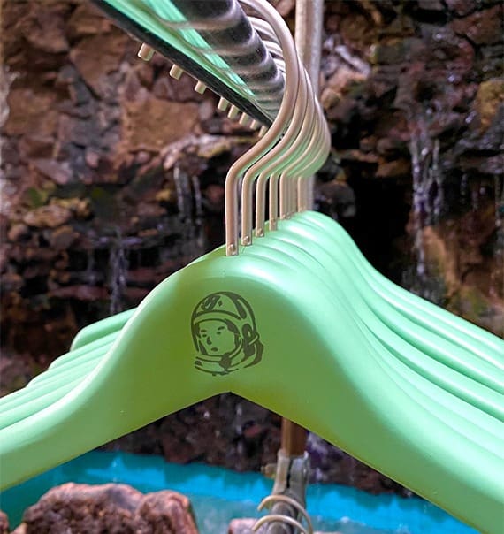 Green hangers display playful astronaut design by water.