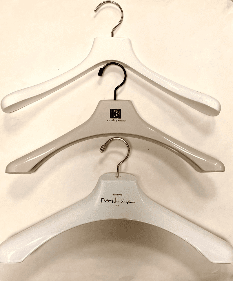 Three clothing hangers are arranged vertically. The top and bottom hangers are white, while the middle one is light gray, featuring a logo labeled "laundry by design."