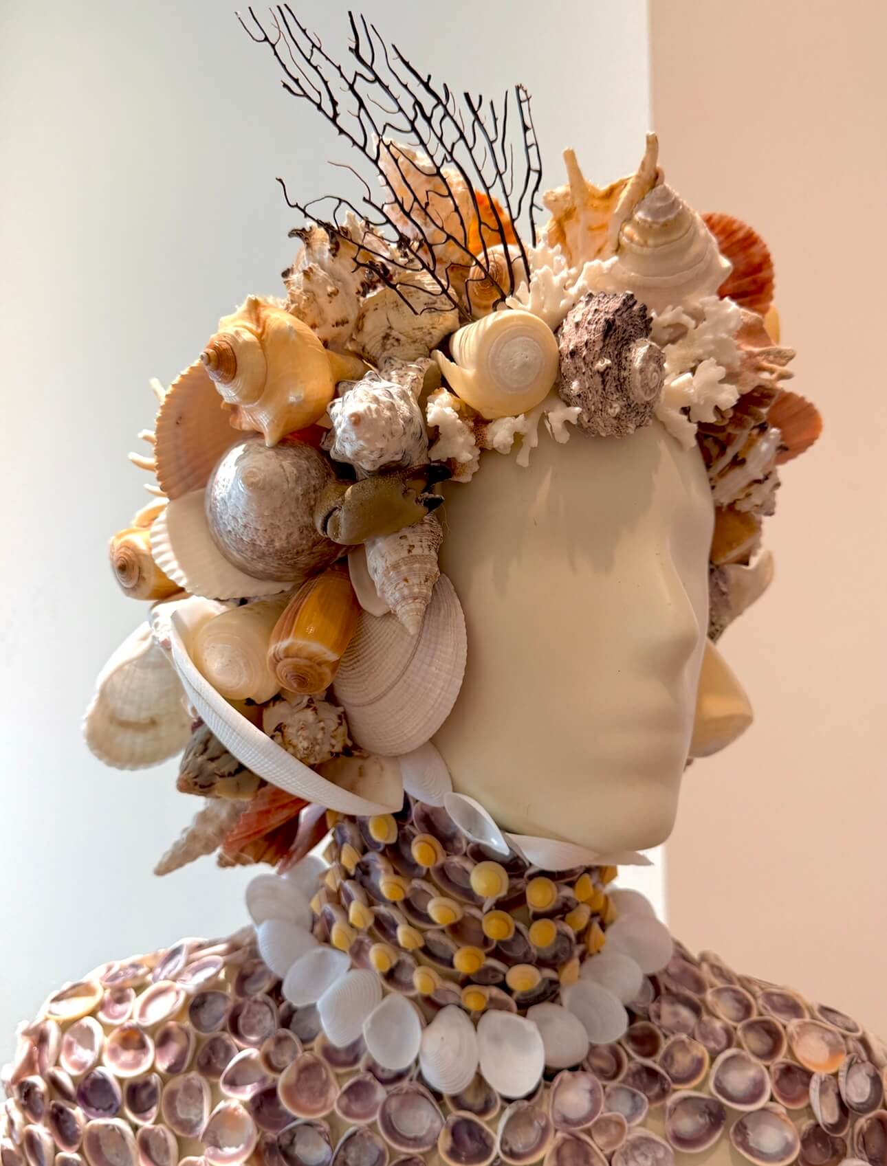 Mannequin wears vibrant seashell headpiece and shell necklace.