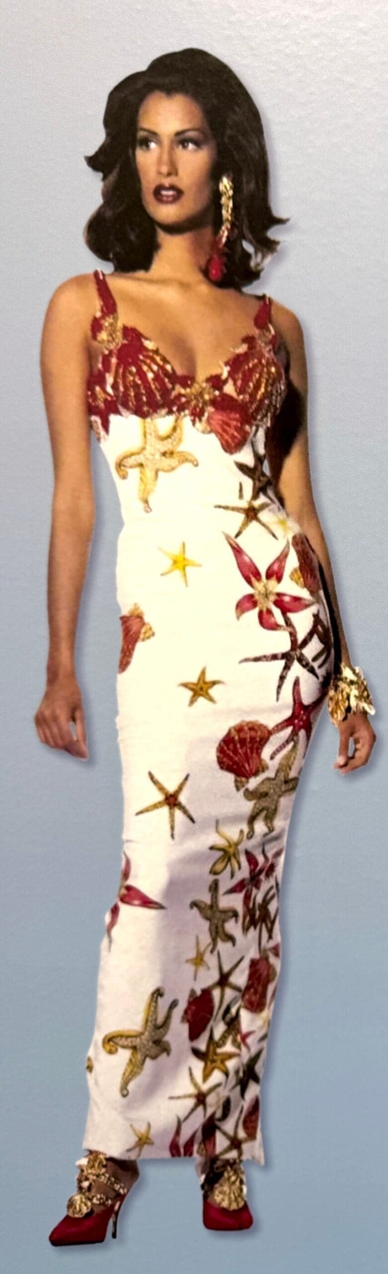 Model wears shell-embellished gown with red shoes.