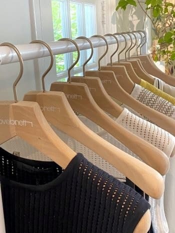Stylish garments on wooden hangers showcase modern textures.