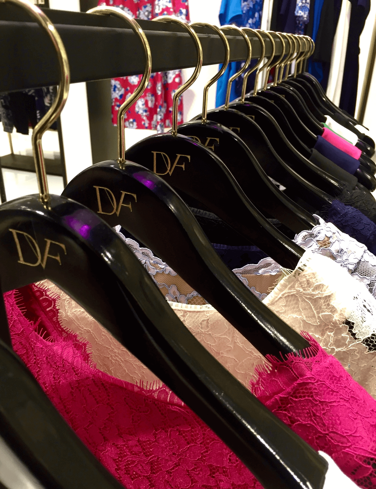 Vibrant lace tops hang on branded black hangers.